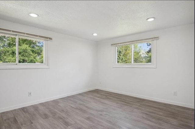 spare room featuring dark hardwood / wood-style flooring, plenty of natural light, and a textured ceiling