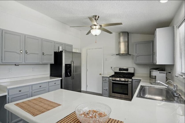 kitchen featuring ceiling fan, wall chimney exhaust hood, gray cabinetry, sink, and appliances with stainless steel finishes