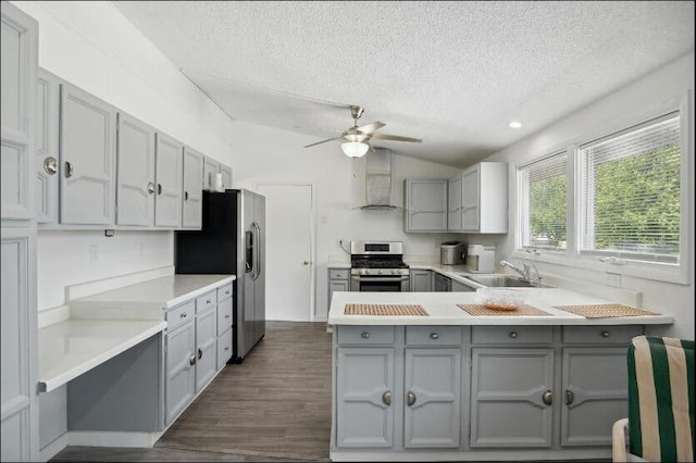 kitchen featuring wall chimney range hood, dark hardwood / wood-style floors, kitchen peninsula, stainless steel appliances, and sink