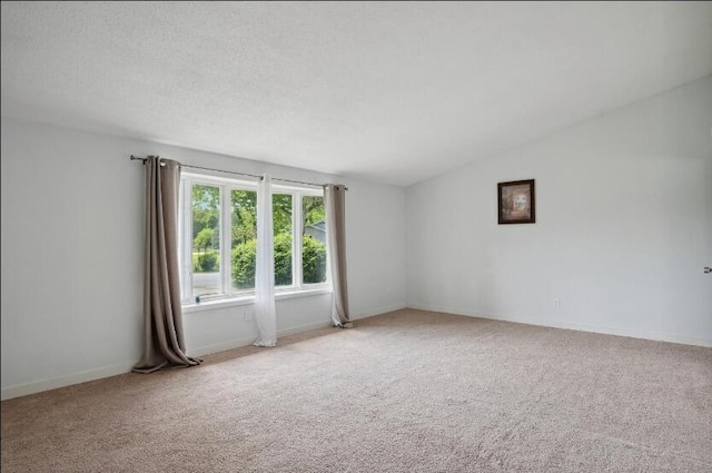 spare room with vaulted ceiling, a textured ceiling, and carpet flooring