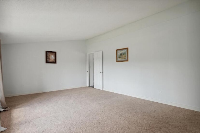 spare room with carpet and vaulted ceiling