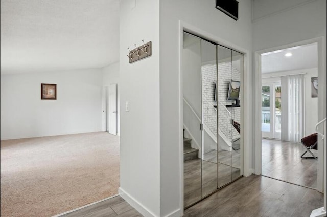 hallway with carpet floors and lofted ceiling