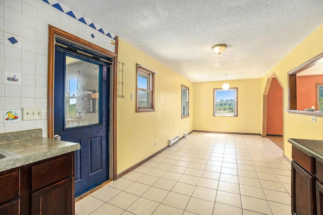 interior space with hanging light fixtures, light tile patterned floors, a baseboard radiator, and a textured ceiling