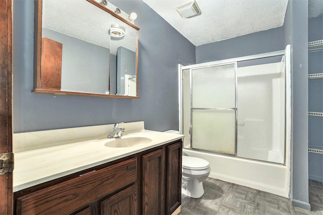 full bathroom with combined bath / shower with glass door, vanity, a textured ceiling, parquet flooring, and toilet