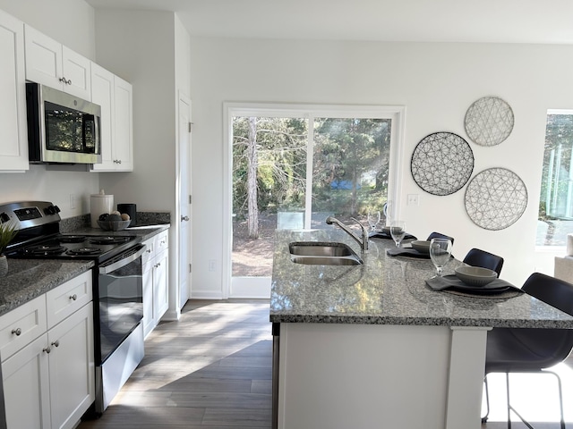 kitchen with dark hardwood / wood-style floors, a kitchen breakfast bar, stainless steel appliances, sink, and white cabinetry