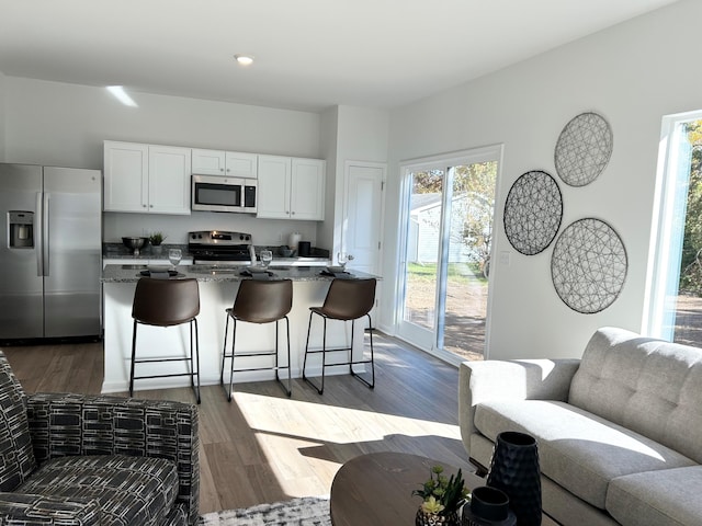 kitchen featuring a healthy amount of sunlight, stainless steel appliances, white cabinetry, and dark stone counters