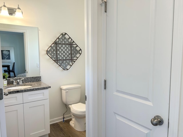 bathroom featuring toilet, hardwood / wood-style flooring, and vanity