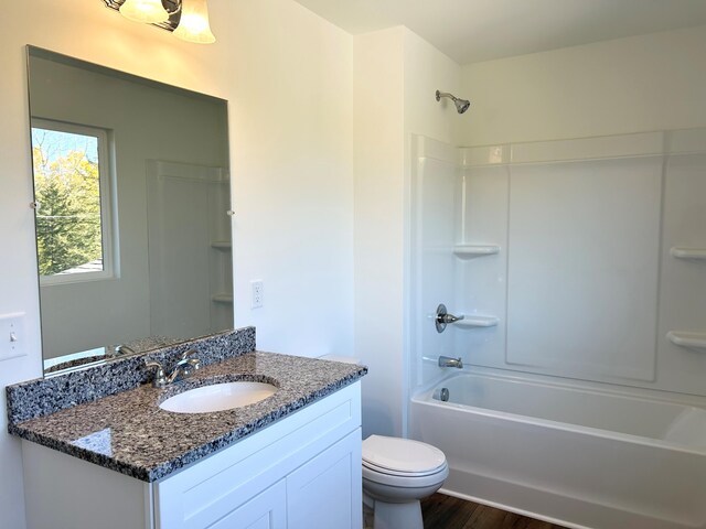 full bathroom with toilet, hardwood / wood-style flooring, vanity, and tub / shower combination