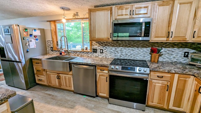 kitchen with sink, appliances with stainless steel finishes, tasteful backsplash, and a textured ceiling