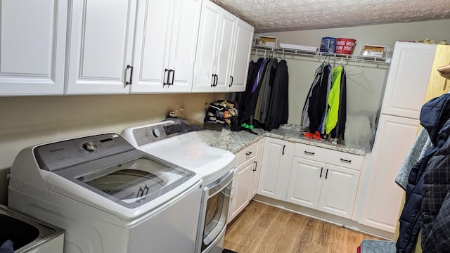 clothes washing area with independent washer and dryer, light hardwood / wood-style flooring, cabinets, and a textured ceiling