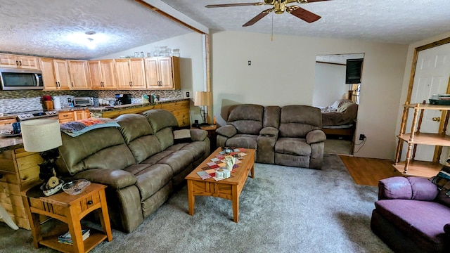 living room with a textured ceiling, ceiling fan, light carpet, and vaulted ceiling with beams