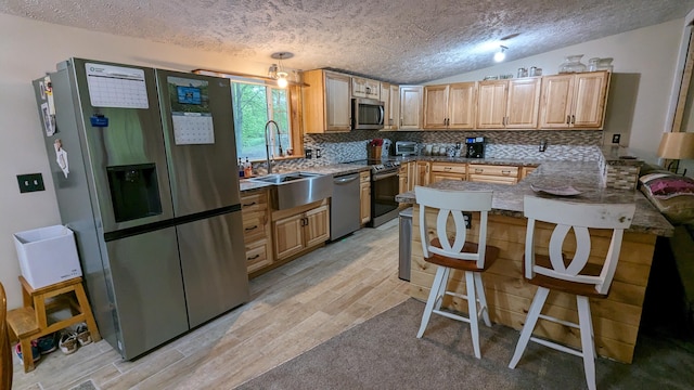 kitchen featuring backsplash, stainless steel appliances, sink, and lofted ceiling