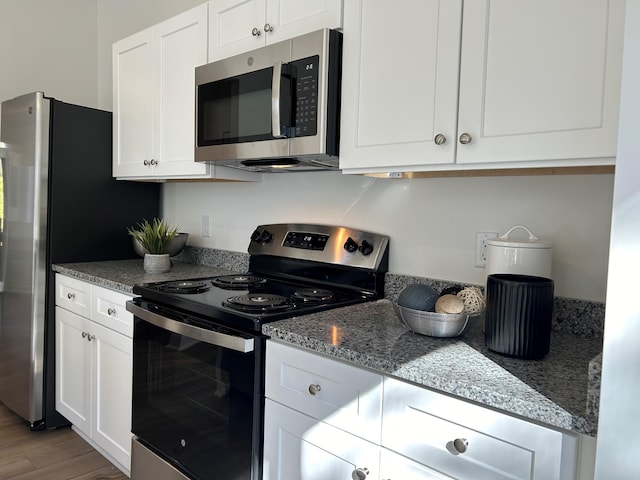 kitchen featuring stone counters, appliances with stainless steel finishes, wood-type flooring, and white cabinets