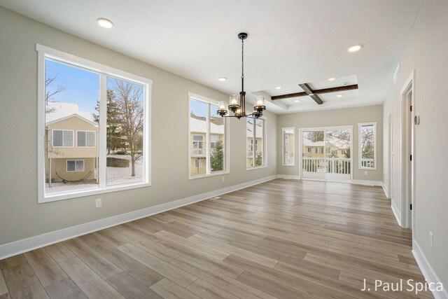 unfurnished dining area with beam ceiling, a wealth of natural light, light hardwood / wood-style flooring, and a chandelier