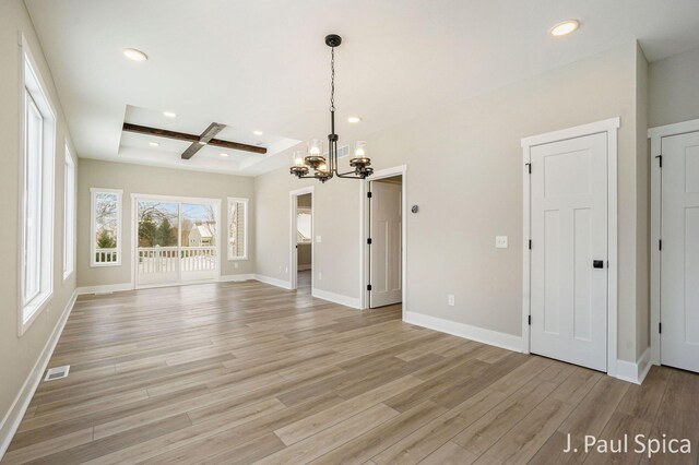 unfurnished living room with an inviting chandelier, coffered ceiling, light wood-type flooring, a tray ceiling, and beam ceiling