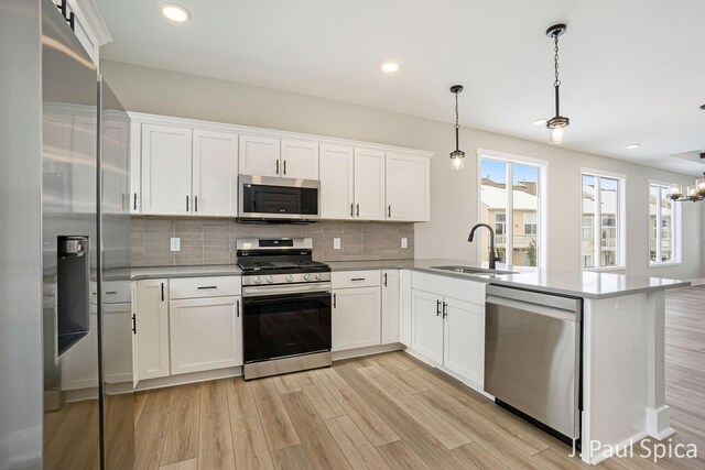 kitchen featuring white cabinets, sink, stainless steel appliances, and hanging light fixtures