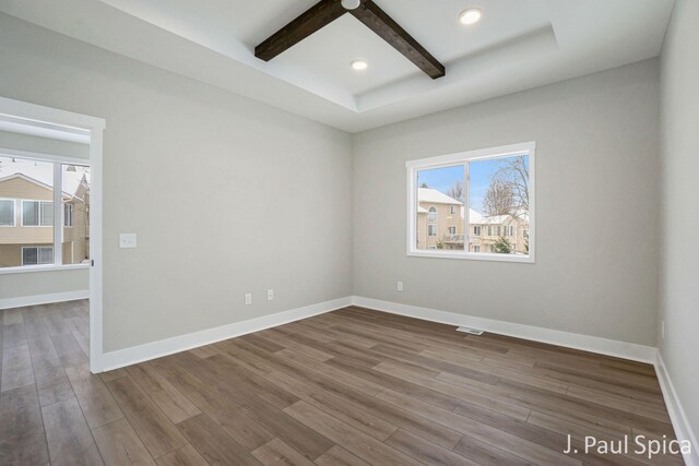 empty room featuring beam ceiling and wood-type flooring