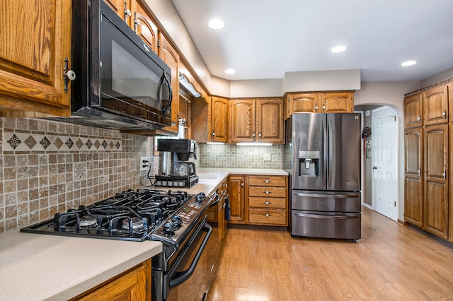 kitchen featuring light hardwood / wood-style flooring, tasteful backsplash, and black appliances