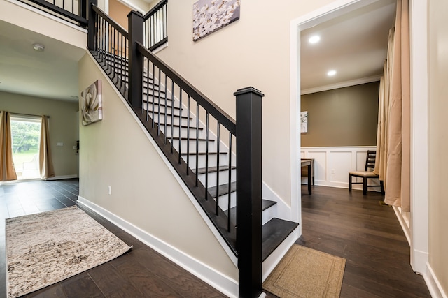 staircase featuring ornamental molding and dark hardwood / wood-style flooring