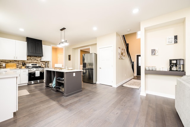 kitchen with white cabinets, appliances with stainless steel finishes, hardwood / wood-style flooring, and a kitchen island