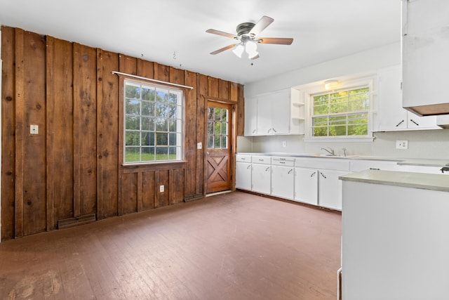 kitchen with plenty of natural light, dark hardwood / wood-style floors, wooden walls, and ceiling fan