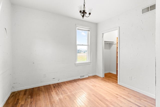 unfurnished bedroom with light hardwood / wood-style floors, a closet, and a chandelier