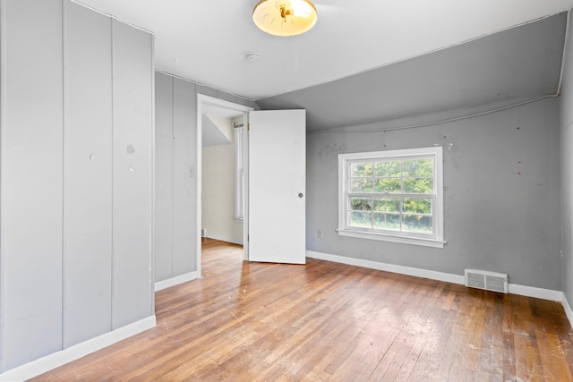 unfurnished room featuring light wood-type flooring and vaulted ceiling