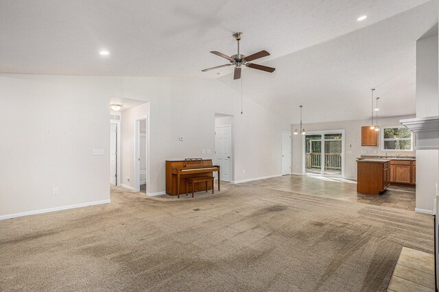 unfurnished living room with ceiling fan, sink, light carpet, and high vaulted ceiling