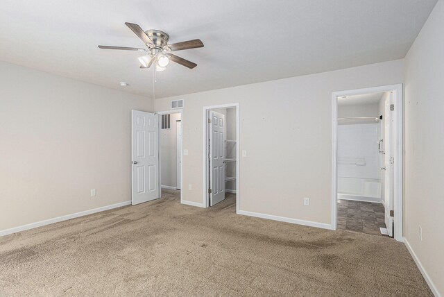 unfurnished bedroom with a closet, ceiling fan, a spacious closet, and light carpet