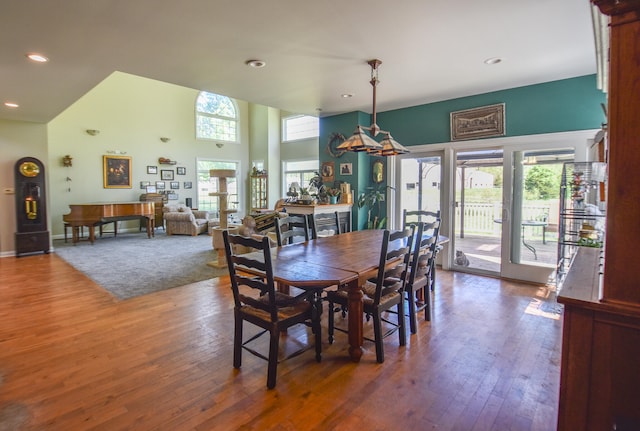 dining area with a towering ceiling, a wealth of natural light, and dark hardwood / wood-style floors