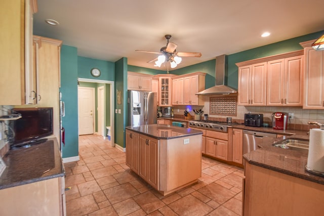 kitchen with wall chimney range hood, a kitchen island, appliances with stainless steel finishes, tasteful backsplash, and ceiling fan