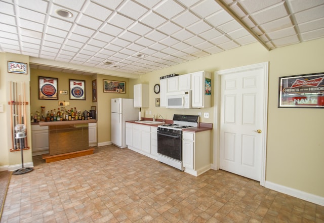 kitchen with white cabinets, sink, white appliances, and light tile floors