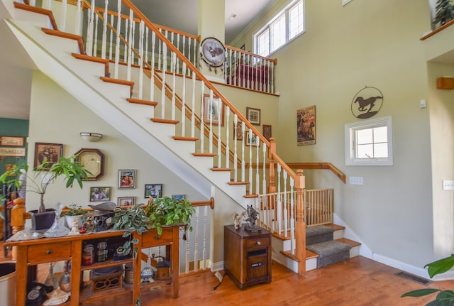 staircase featuring wood-type flooring and a towering ceiling