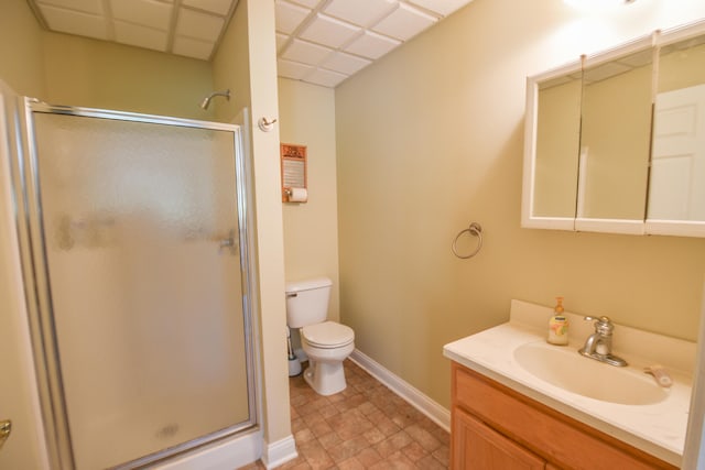 bathroom with a paneled ceiling, tile floors, a shower with door, vanity, and toilet