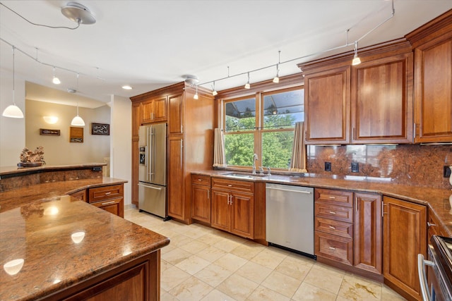 kitchen featuring tasteful backsplash, stainless steel appliances, sink, pendant lighting, and stone counters