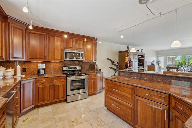 kitchen featuring rail lighting, tasteful backsplash, dark stone countertops, decorative light fixtures, and appliances with stainless steel finishes