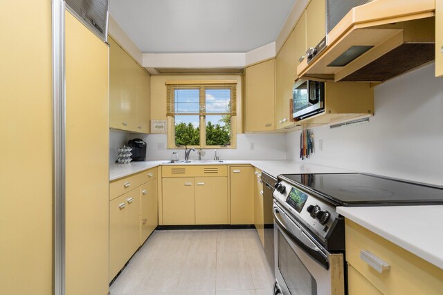 kitchen with wall chimney range hood, sink, light tile flooring, and stainless steel appliances