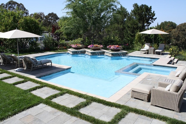 view of swimming pool featuring a patio area, pool water feature, and an in ground hot tub