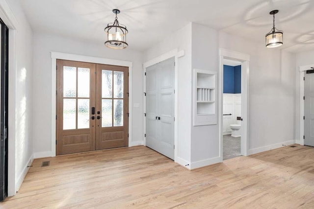 foyer featuring light hardwood / wood-style floors, french doors, and a chandelier