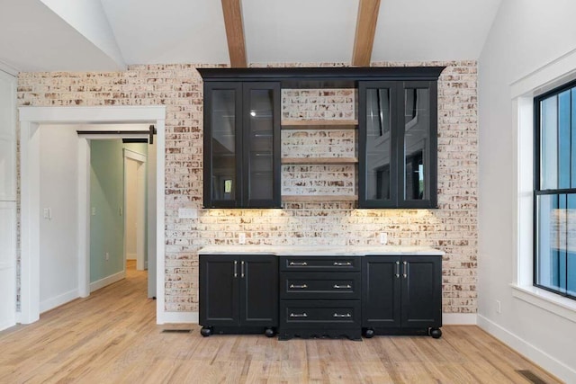 bar with lofted ceiling, a barn door, and light wood-type flooring