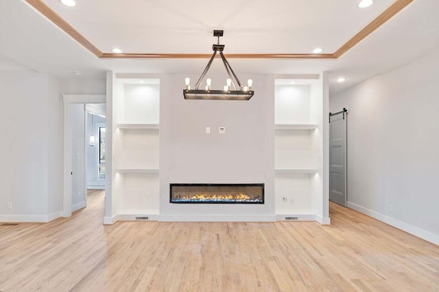 unfurnished living room with hardwood / wood-style flooring, a barn door, built in features, and a tray ceiling