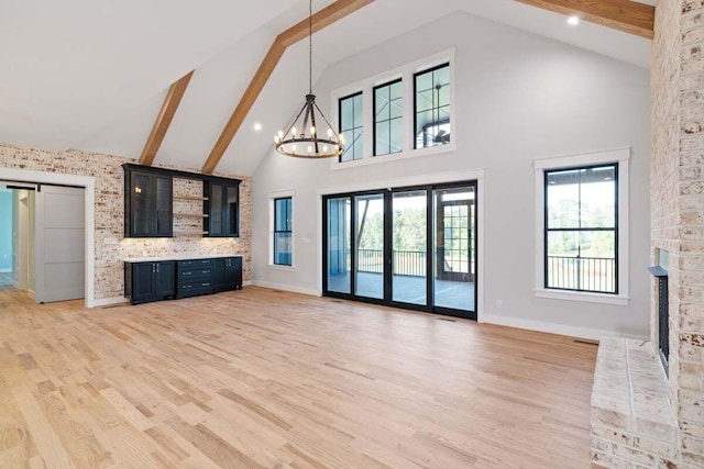 unfurnished living room with beam ceiling, hardwood / wood-style flooring, a chandelier, and high vaulted ceiling