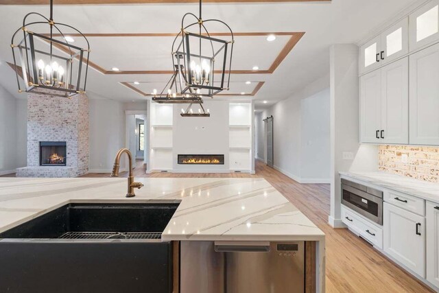 kitchen featuring white cabinetry, a large fireplace, and light stone countertops