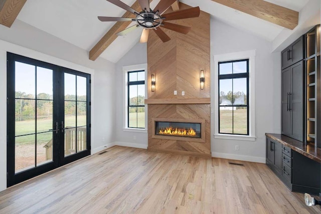 unfurnished living room with beamed ceiling, french doors, a high end fireplace, and light hardwood / wood-style flooring