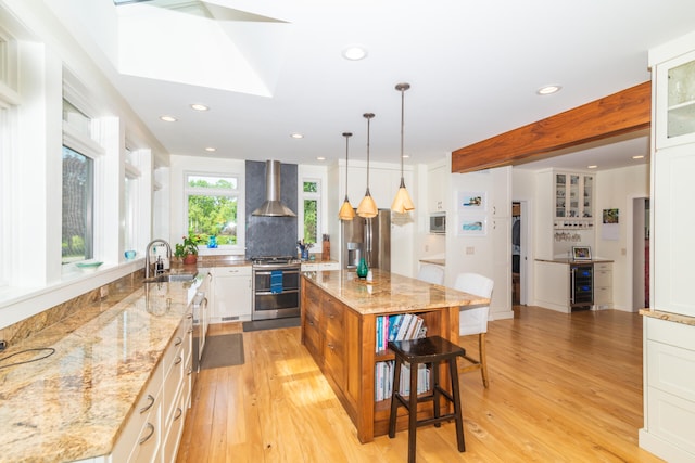 kitchen with wine cooler, white cabinetry, wall chimney exhaust hood, a center island, and appliances with stainless steel finishes