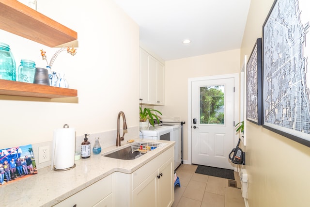 laundry area featuring washing machine and dryer, sink, cabinets, and light tile floors