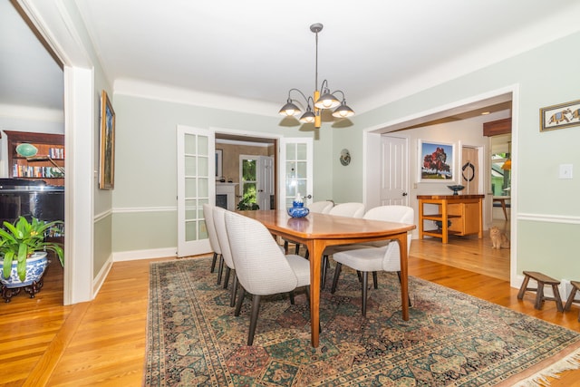 dining space with a notable chandelier, light hardwood / wood-style flooring, and french doors