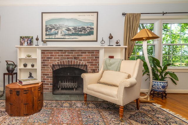 living room with crown molding, hardwood / wood-style flooring, and a brick fireplace