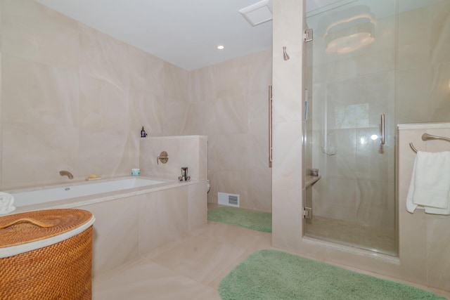 bathroom featuring tile floors, separate shower and tub, and tile walls