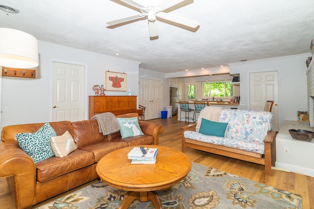 living room with crown molding, hardwood / wood-style flooring, ceiling fan, and a textured ceiling